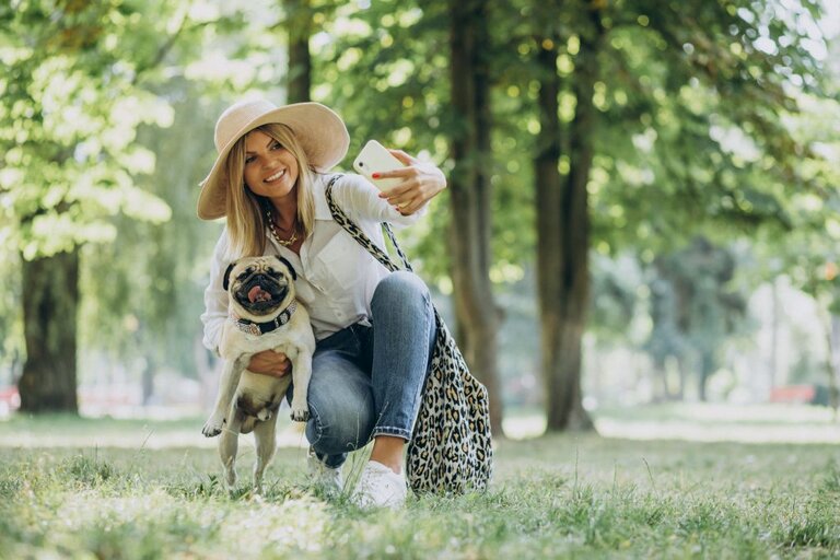 Owner taking selfie with pug in a park